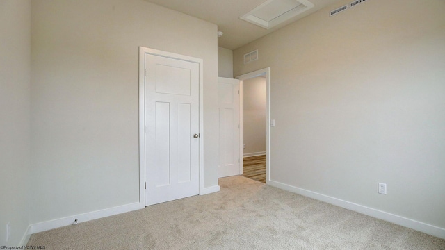 carpeted empty room featuring attic access, baseboards, and visible vents