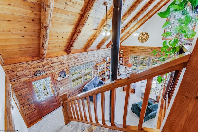 staircase with beam ceiling, high vaulted ceiling, wood ceiling, and a wood stove