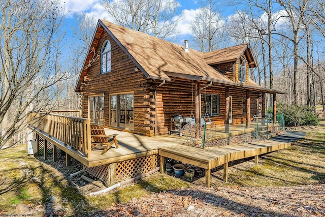 exterior space featuring log siding, a wooden deck, and roof with shingles