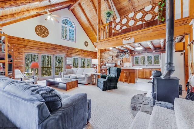 living area with light carpet, a ceiling fan, wood ceiling, and a wood stove