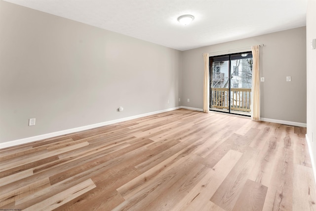 spare room featuring baseboards and light wood-style floors