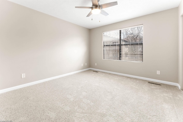 carpeted spare room with visible vents, baseboards, and a ceiling fan