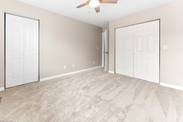 unfurnished bedroom with baseboards, two closets, and carpet flooring