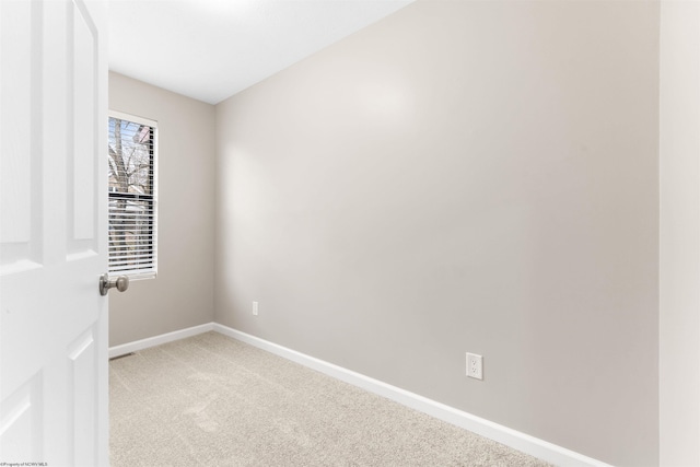 spare room with baseboards and light carpet