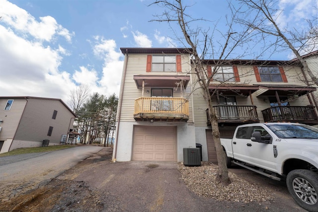 townhome / multi-family property featuring aphalt driveway, central air condition unit, and a garage