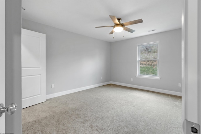 carpeted spare room featuring baseboards, visible vents, and ceiling fan