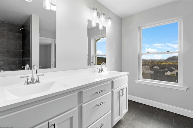 full bath with double vanity, baseboards, a tile shower, and a sink