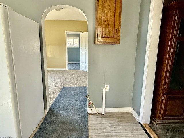 hallway featuring arched walkways and baseboards