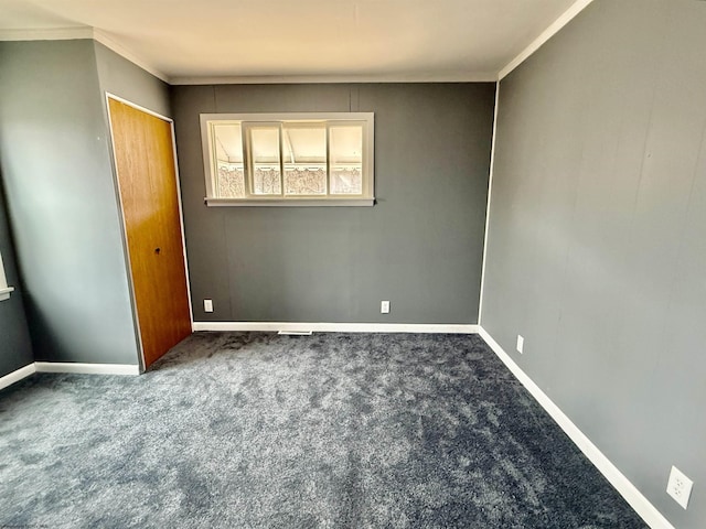 unfurnished bedroom with a closet, crown molding, baseboards, and carpet floors