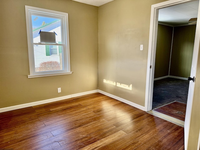 empty room with baseboards and hardwood / wood-style flooring