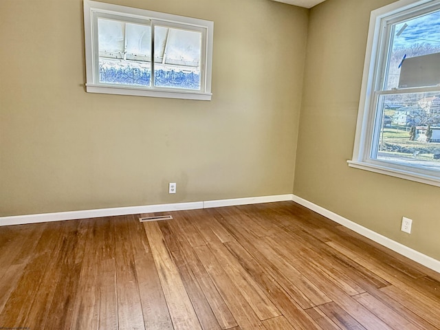 unfurnished room featuring visible vents, wood finished floors, and baseboards