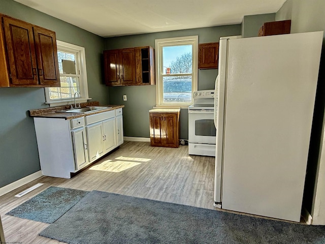 kitchen featuring visible vents, baseboards, light wood-style flooring, white appliances, and a sink