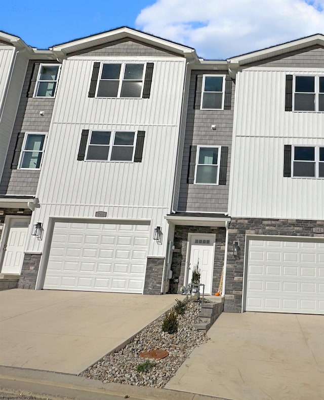 townhome / multi-family property with stone siding, concrete driveway, and a garage