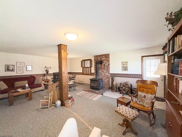 living room featuring a wood stove, carpet flooring, and wainscoting