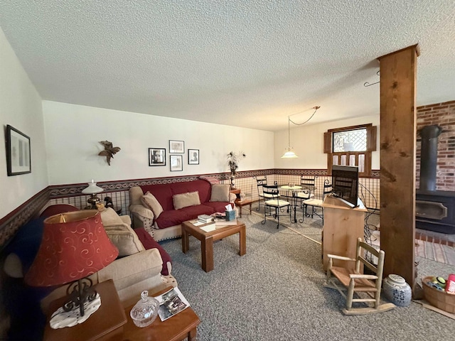 carpeted living area with a textured ceiling, a wood stove, and wainscoting