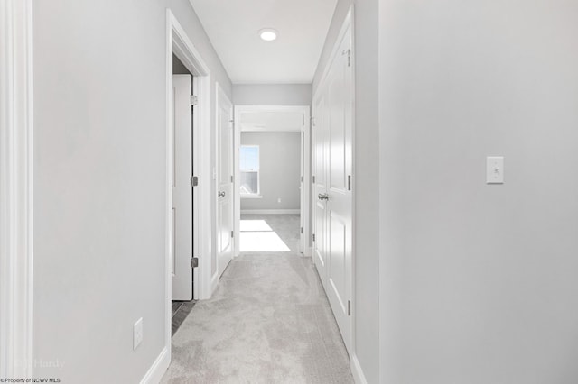 hallway with light colored carpet and baseboards