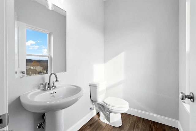 bathroom with toilet, baseboards, and wood finished floors