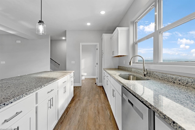 kitchen featuring white cabinetry, light wood-style flooring, a sink, hanging light fixtures, and dishwasher