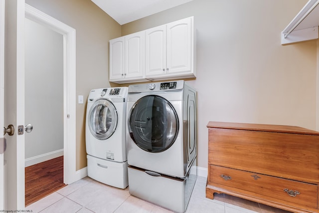 washroom with cabinet space, light tile patterned floors, separate washer and dryer, and baseboards