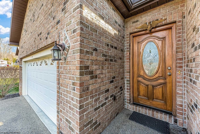 doorway to property featuring brick siding and a garage