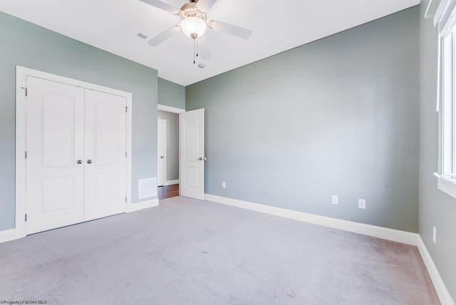 unfurnished bedroom featuring baseboards, visible vents, carpet floors, and a closet