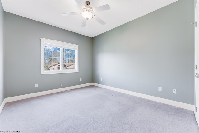 carpeted spare room featuring visible vents, baseboards, and ceiling fan