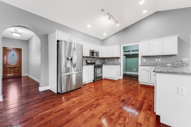 kitchen featuring a sink, arched walkways, white cabinetry, and stainless steel appliances