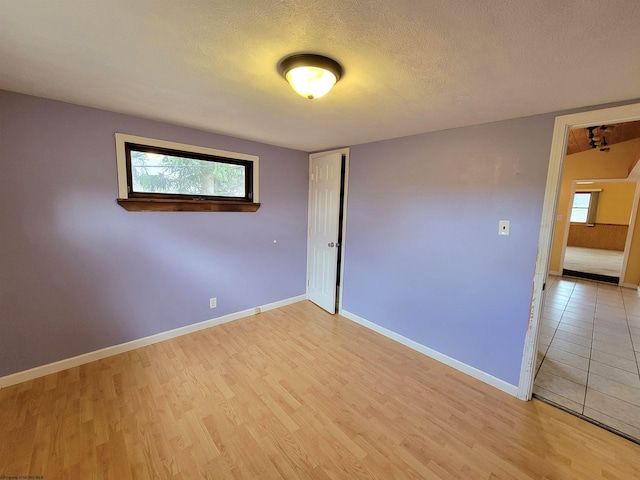 empty room with a healthy amount of sunlight, light wood-style floors, and a textured ceiling