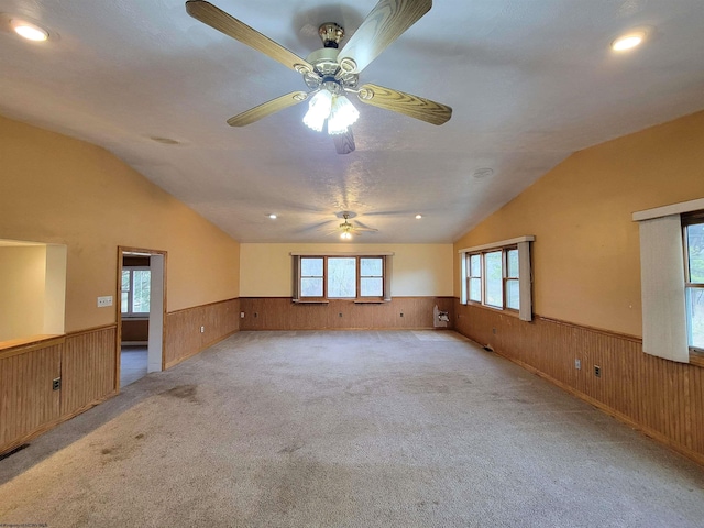 spare room featuring a ceiling fan, wood walls, and wainscoting