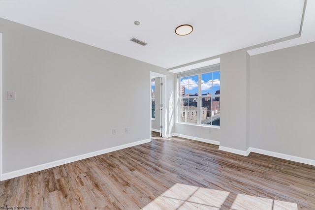 spare room with visible vents, baseboards, and wood finished floors