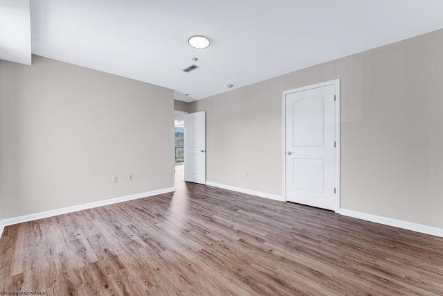 empty room featuring visible vents, baseboards, and wood finished floors