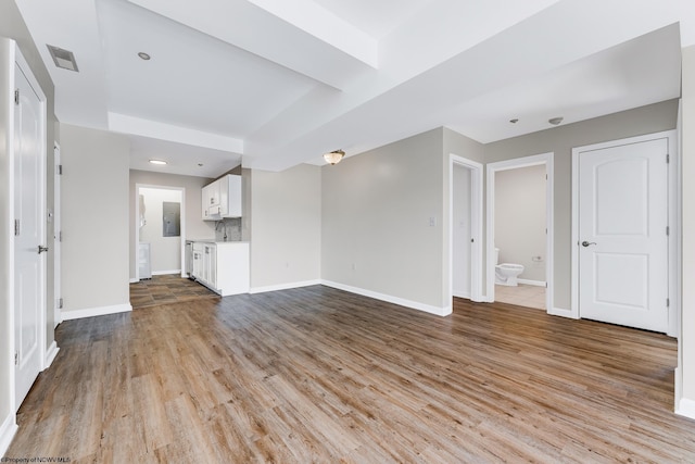 unfurnished living room featuring electric panel, visible vents, baseboards, and wood finished floors