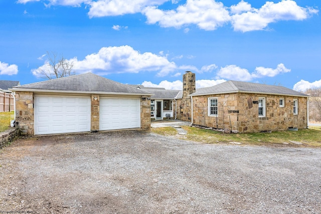 single story home with roof with shingles, a chimney, a garage, stone siding, and dirt driveway