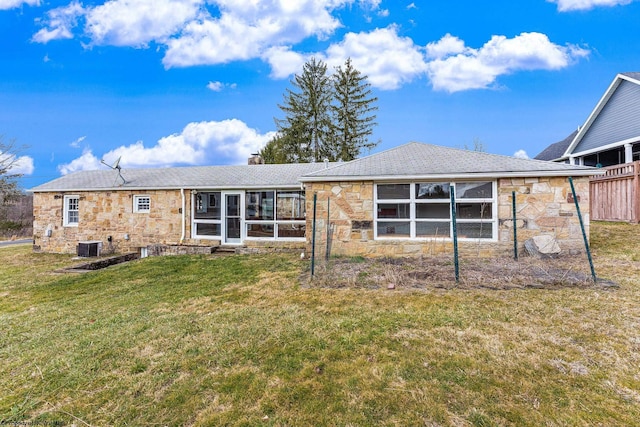 rear view of property featuring central AC unit, a lawn, a chimney, a sunroom, and stone siding