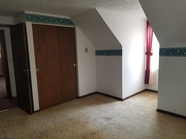 bonus room with lofted ceiling, light colored carpet, baseboards, and a textured ceiling