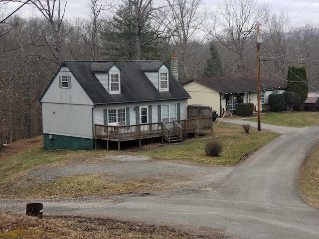 new england style home featuring driveway, a chimney, and a deck