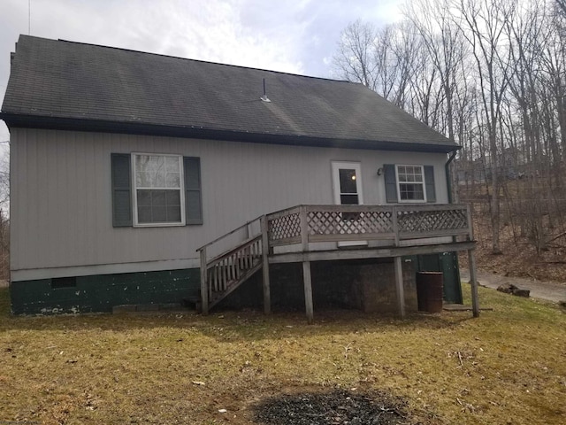 rear view of house featuring a shingled roof and a wooden deck