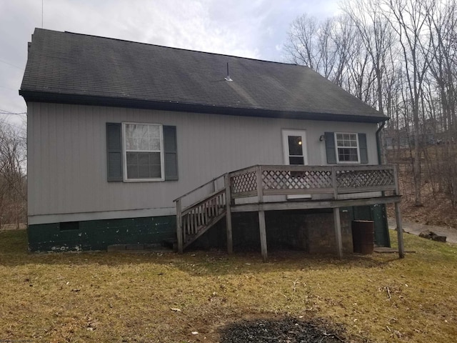 rear view of house with a yard, a shingled roof, and a deck