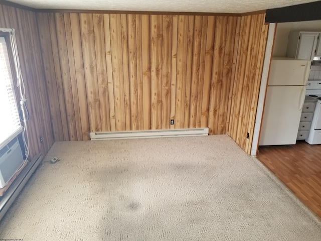 spare room with a baseboard radiator, baseboard heating, and wood walls