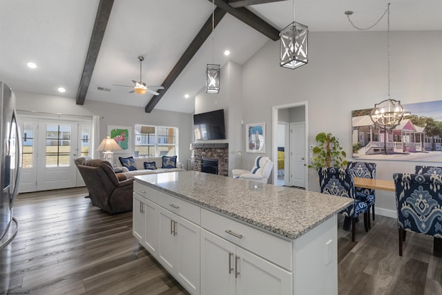 kitchen featuring dark wood-type flooring, a stone fireplace, open floor plan, and ceiling fan with notable chandelier
