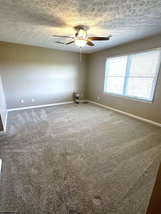 carpeted spare room featuring baseboards, a textured ceiling, and ceiling fan