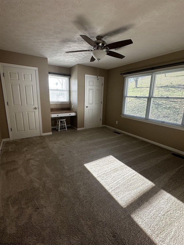 unfurnished bedroom featuring visible vents, baseboards, a textured ceiling, and carpet flooring