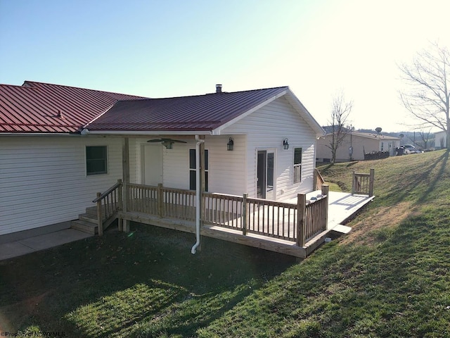 rear view of property featuring a wooden deck, ceiling fan, metal roof, and a yard