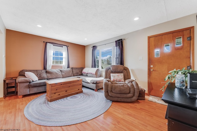 living area with recessed lighting, light wood finished floors, and a textured ceiling