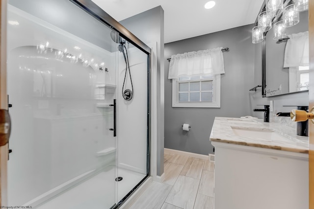 bathroom featuring baseboards, a stall shower, and vanity