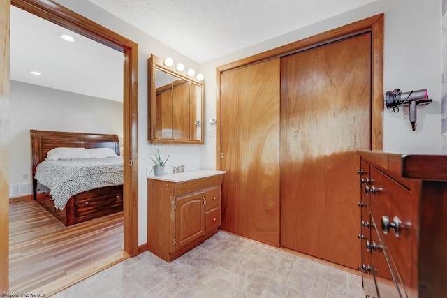 ensuite bathroom with visible vents, baseboards, vanity, recessed lighting, and ensuite bath