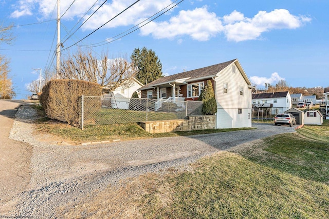 view of front of house featuring gravel driveway, a front yard, and a fenced front yard