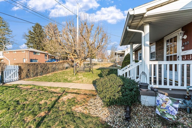 view of yard featuring a gate, fence, and covered porch
