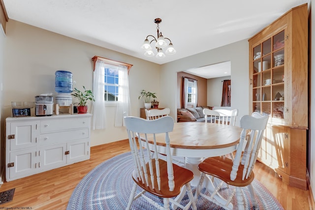 dining area featuring a notable chandelier, visible vents, and light wood-type flooring