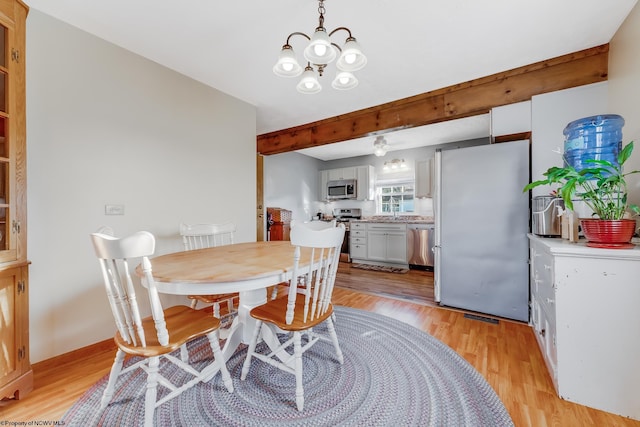 dining area with beamed ceiling, baseboards, light wood-style floors, and an inviting chandelier